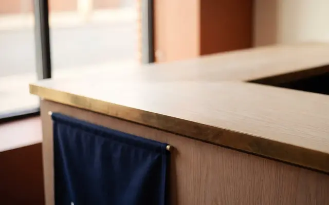 An empty oak shop counter in daylight with a navy cloth hanging from its edge