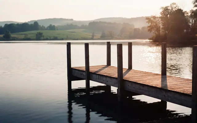 A wooden dock reaching into a calm lake at sunset